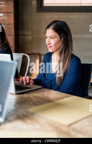 A woman focused on her laptop while working from a cafe, representing a modern, flexible work environment. Stock Photo