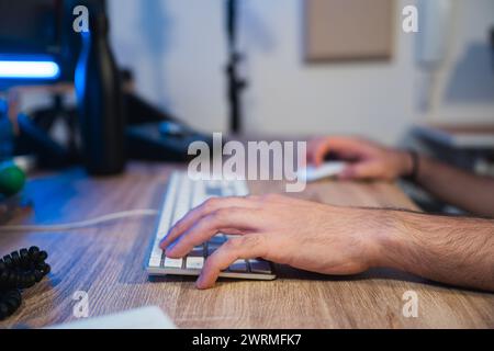 Cropped unrecognizable sound engineer's hands editing audio on a keyboard in a professional studio setting. Stock Photo