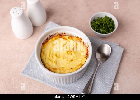 Shepherd's pie in a portioned white baking dish. Homemade traditional casserole (gratin) with minced meat and mashed potatoes. Selective focus, close- Stock Photo
