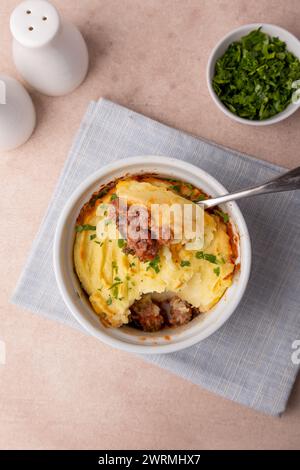 Shepherd's pie in a portioned white baking dish. Homemade traditional casserole (gratin) with minced meat and mashed potatoes. Selective focus, close- Stock Photo