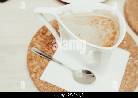 Coffee cup on cork plate, vintage filtered. Latte concept. Coffee with milk in white cup. Coffee wallpaper. Breakfast table. Morning drinks. Stock Photo