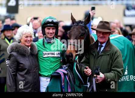 Trainer Willie Mullins, wife Jackie Mullins and jockey Patrick Mullins pose for a photo with Jasmin De Vaux as they celebrate winning the Weatherbys Champion Bumper on day two of the 2024 Cheltenham Festival at Cheltenham Racecourse. Willie Mullins reached the magical 100-winner mark at the Cheltenham Festival as the Patrick Mullins-ridden Jasmin De Vaux provided him with a 13th victory in the Weatherbys Champion Bumper. Picture date: Wednesday March 13, 2024. Stock Photo