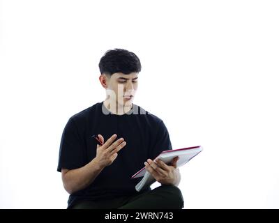 Young man performs calculations with his fingers, holds notebook in hand, ready to record his financial thoughts Stock Photo