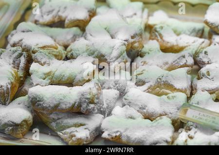 A tray filled with assorted pastries like croissants and muffins is shown up close, each delicately covered in a dusting of powdered sugar. Stock Photo