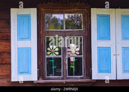 A window of an old country house with wooden shutters and flowers behind the glass Stock Photo
