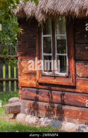 A window of an old country house with wooden shutters and flowers behind the glass Stock Photo