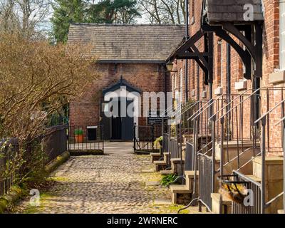 A row of traditional cottages with cobble path leading to Styal Primary School in the village of Styal. Wilmslow, Cheshire, UK Stock Photo