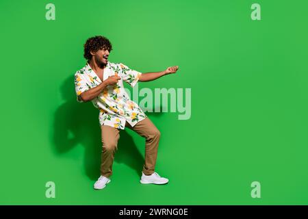 Full size photo of pretty young male pulling heavy object dressed stylish citrus print outfit isolated on green color background Stock Photo