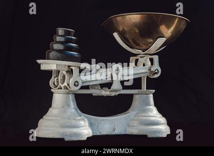 Classic weight scale Isolated on dark background. Old obsolete manual weighing scales and Iron Brass Tray with set of cast iron weights. Antique balan Stock Photo