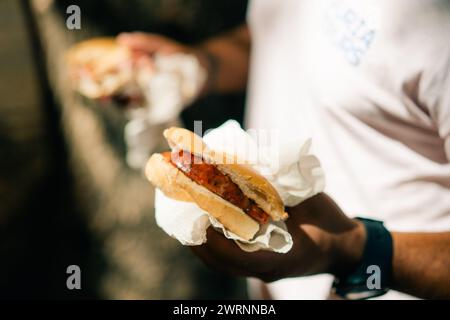 man eating traditional Argentine choripan sandwich at a street food market. High quality photo Stock Photo
