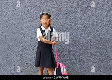 4 year old Latina brunette girl with eyeglasses, uniform and backpack walks to school this back to school Stock Photo