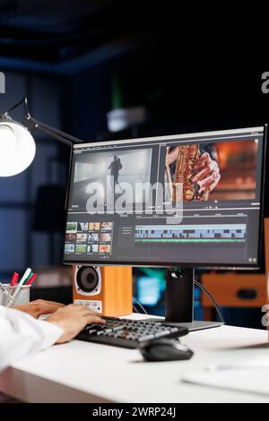 Male cinematographer working with footage and sound, editing new project, cutting film montage seated at office desk. Detailed view of man using computer processing movie in post production software. Stock Photo
