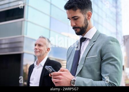 Attractive suit young business man typing concentrated on phone outside office building. Copy space. Stock Photo