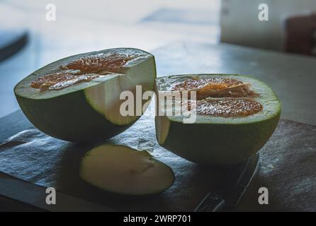 A halved Pomelo, ready to be eaten, sits on a wooden cutting board. Stock Photo