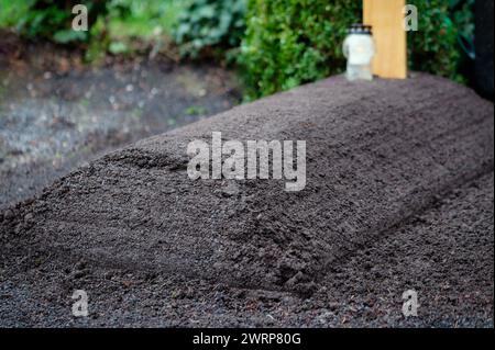 fresh grave in a cemetery with mounded earth without flowers and decorations Stock Photo