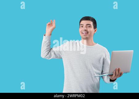 Male programmer with laptop pointing at something on blue background Stock Photo