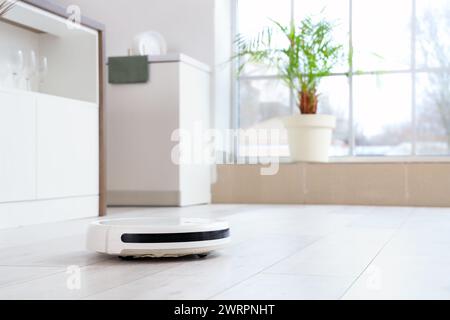 Robot vacuum cleaner on floor in kitchen, closeup Stock Photo