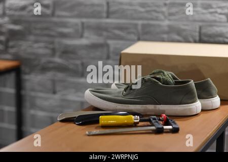 Sneakers with tools on shelf in shoemaker's workshop, closeup Stock Photo