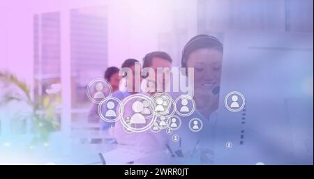 Image of network of digital people icons over team of colleagues with phone headsets in office Stock Photo