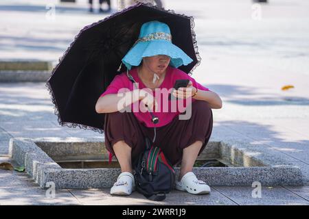 Kuala Lumpur, Malaysia 14 March 2024 . A tourist shelters under an umbrella on a hot and humid day in Kuala Lumpur. Kuala Lumpur  experiences a tropical climate and  hot and humid conditions throughout the year with temperatures ranging from 22ºC to 35ºC throughout the  year .Credit: amer ghazzal/Alamy Live News Stock Photo