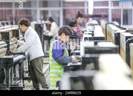 HUZHOU, CHINA - MARCH 14, 2024 - Workers are assembling pianos at a workshop of a piano company in Huzhou, East China's Zhejiang province, March 14, 2 Stock Photo