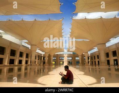 Jakarta, Indonesia-March 26, 2025: A Muslim man prays in the corridor outside a mosque. Stock Photo