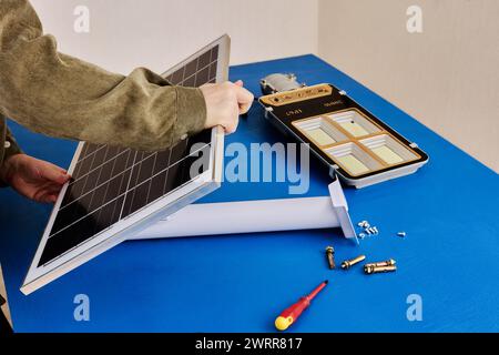 Electrician installs solar panel on mounting bracket holder for stand-alone cordless LED street light. Stock Photo