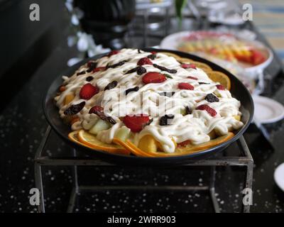 fruit salad in a black ceramic container on the table Stock Photo