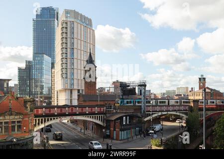 A train crossing over a railway bridge into Deansgate Station, Manchester, UK with Castle Wharf and Deansgate Square apartments in the background Stock Photo