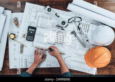 Top view Engineering working with drawings inspection and writing on the office desk and Calculator, triangle ruler, safety glasses, compass, vernier Stock Photo