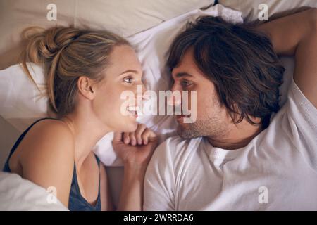 Love, relax and couple in a bed talking, bonding and resting in their home from above. Wake up, conversation and people in a bedroom with morning Stock Photo