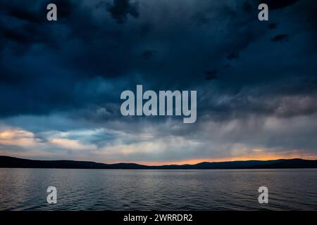 Storm clouds over a picturesque lake at sunset Stock Photo