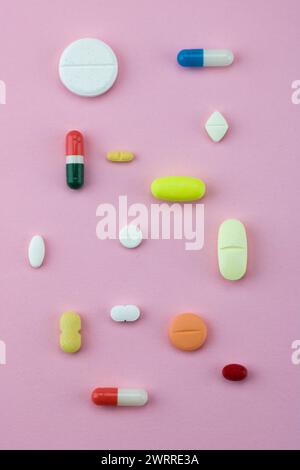 group of capsules and pills in different colors and shape isolated on pink background Stock Photo
