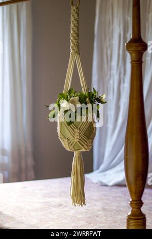 macrame pot holder in cotton rope hanging on canopy bed, home decor Stock Photo