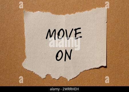 Move on words written on torn paper piece with brown background. Conceptual symbol. Copy space. Stock Photo