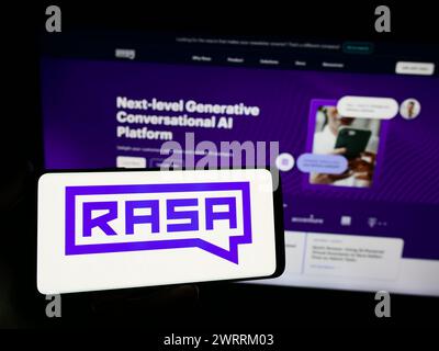 Person holding smartphone with logo of US conversational AI company Rasa Technologies Inc. in front of website. Focus on phone display. Stock Photo