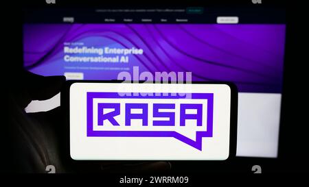 Person holding cellphone with logo of US conversational AI company Rasa Technologies Inc. in front of business webpage. Focus on phone display. Stock Photo