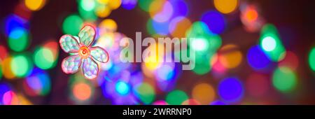 Multicolored garland flower against background of multicolored lights on Christmas night, beautiful New Year lights create atmosphere of wonder and ho Stock Photo