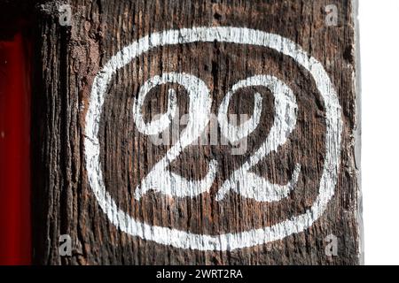 White house license plate number twenty-two painted on a dark wooden beam, Germany Stock Photo