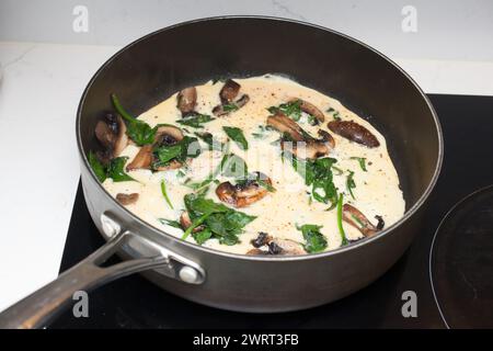A spinach and mushroom omelette being cooking in a frying pan Stock Photo