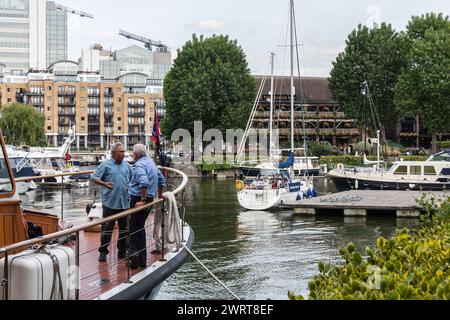 Two mature men stood talking on a boat at Saint Katherine's dock marina in London,England,UK Stock Photo