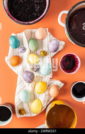 The process of dyeing Easter eggs with natural dyes, hibiscus and turmeric, onion peel and red cabbage, beetroot juice, paint containers and colored eggs on a napkin Stock Photo