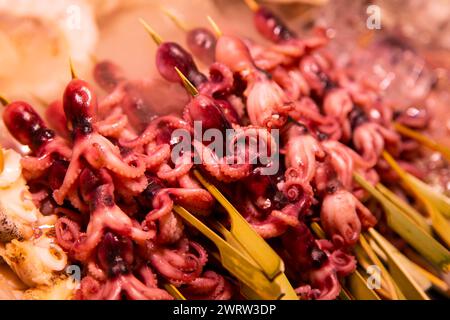 Tiny octopus with boiled quail egg inside in a market stall in Nishiki fish market in Kyoto, Japan. Stock Photo