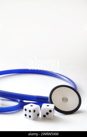 Blue stethoscope beside two dice on white background Stock Photo
