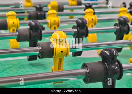 Foosball table game with plastic figures and metal rods low angle view, isolated selective focus. Popular tabletop soccer game played worldwide. Stock Photo