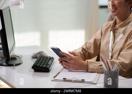 Cropped image of smiling office worker texting friends instead of working Stock Photo