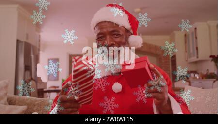 Image of snow falling over smiling man wearing santa claus costume and having image call Stock Photo