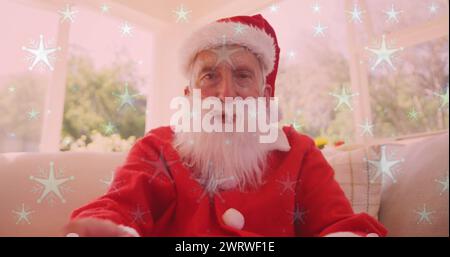 Image of snow falling over smiling man wearing santa claus costume and having image call Stock Photo