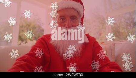 Image of snow falling over smiling man wearing santa claus costume and having image call Stock Photo