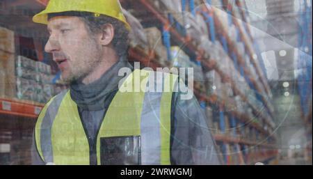 Composite image of surveillance camera over caucasian male supervisor walking at warehouse Stock Photo